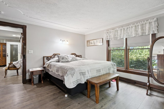 bedroom featuring a textured ceiling, crown molding, and hardwood / wood-style floors