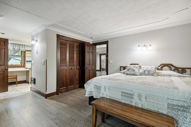 bedroom with hardwood / wood-style floors, a closet, crown molding, and a textured ceiling