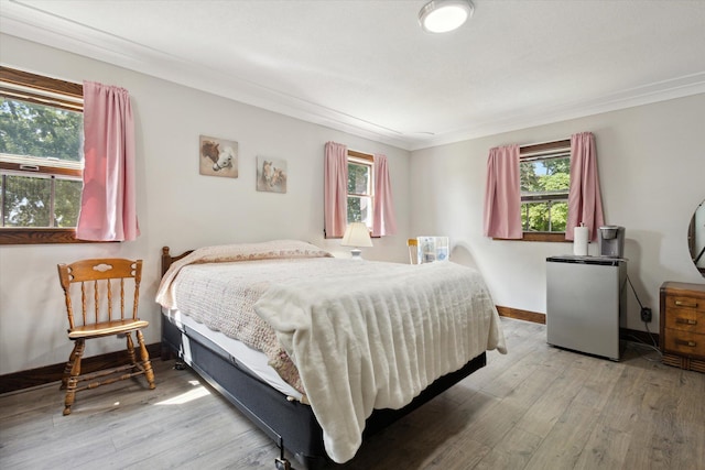 bedroom featuring ornamental molding, stainless steel fridge, and hardwood / wood-style flooring