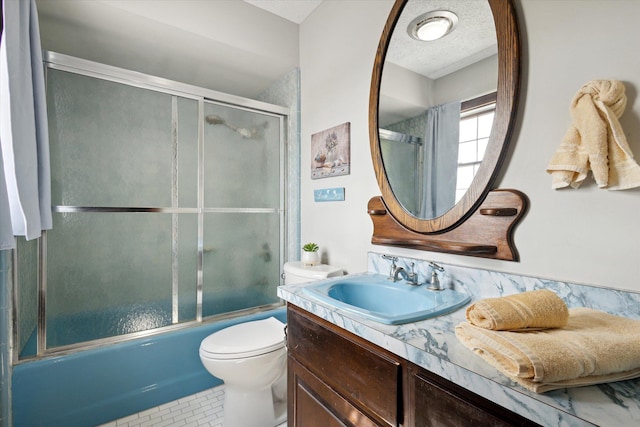 full bathroom featuring a textured ceiling, vanity, combined bath / shower with glass door, tile patterned flooring, and toilet