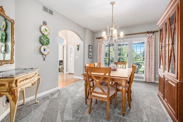 dining area featuring light carpet and a notable chandelier