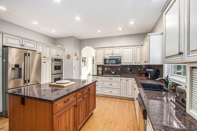 kitchen featuring a center island, stainless steel appliances, light hardwood / wood-style flooring, and dark stone counters