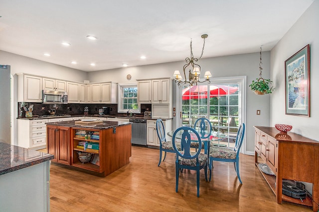 kitchen featuring an inviting chandelier, light hardwood / wood-style flooring, a center island, stainless steel appliances, and dark stone countertops