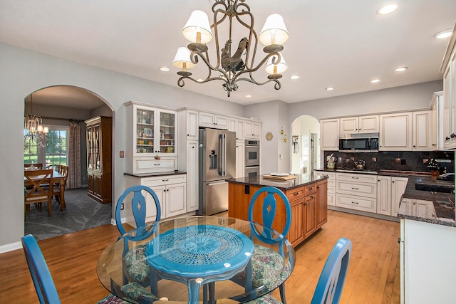 kitchen with white cabinets, light wood-type flooring, appliances with stainless steel finishes, a chandelier, and a kitchen island