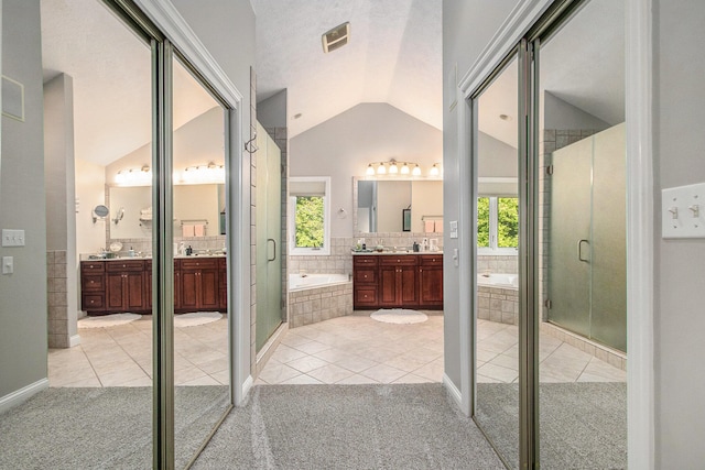 bathroom featuring vanity, vaulted ceiling, independent shower and bath, and tile patterned floors