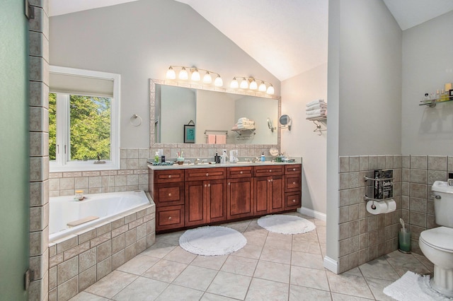 bathroom featuring tile patterned flooring, vaulted ceiling, toilet, tiled tub, and vanity