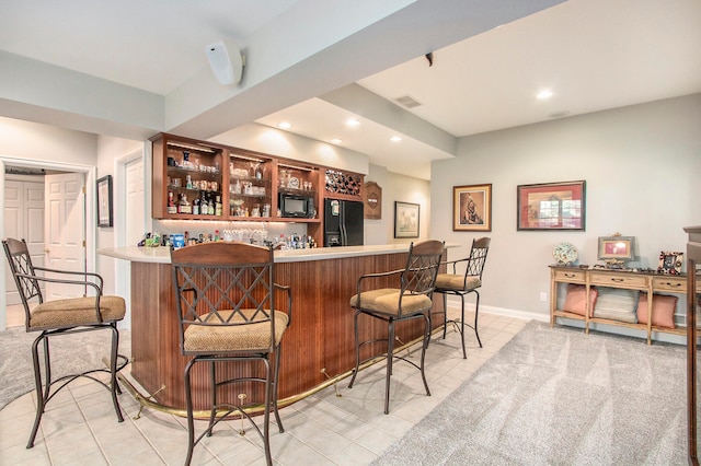 bar with black appliances and light tile patterned floors