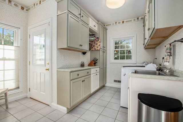 kitchen with light tile patterned floors, sink, washer and clothes dryer, and a healthy amount of sunlight