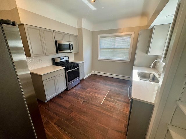 kitchen featuring dark wood-type flooring, a baseboard heating unit, appliances with stainless steel finishes, and sink