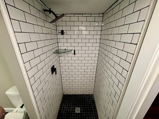 bathroom featuring toilet, a tile shower, and tile patterned floors