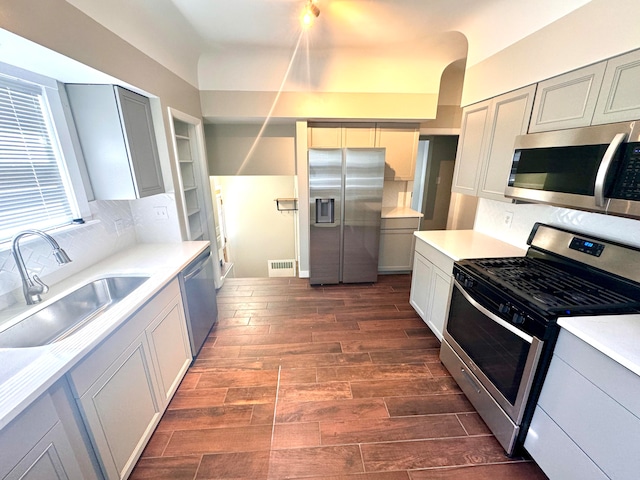 kitchen with dark hardwood / wood-style floors, tasteful backsplash, stainless steel appliances, sink, and gray cabinets