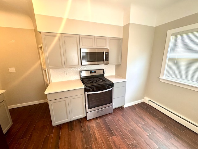 kitchen featuring a baseboard heating unit, appliances with stainless steel finishes, dark hardwood / wood-style flooring, gray cabinets, and decorative backsplash