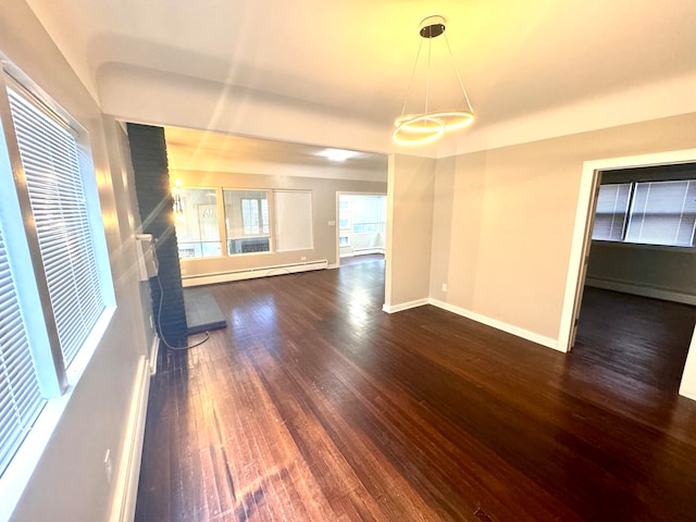 unfurnished living room with dark wood-type flooring, a fireplace, baseboard heating, and a chandelier