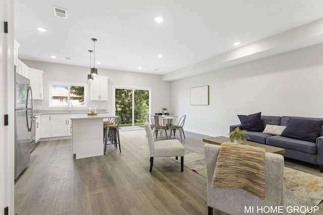 living room with light wood finished floors, visible vents, recessed lighting, and baseboards