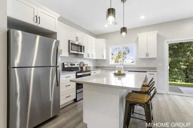 kitchen featuring appliances with stainless steel finishes, light hardwood / wood-style flooring, a kitchen island, and white cabinets