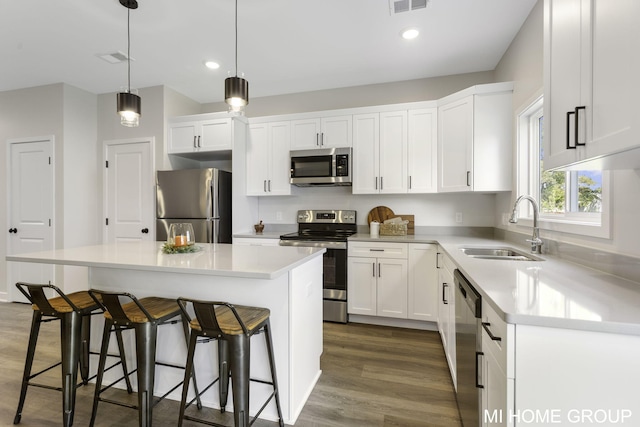 kitchen with dark hardwood / wood-style floors, a center island, stainless steel appliances, sink, and white cabinets