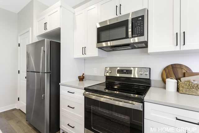 kitchen with dark hardwood / wood-style floors, appliances with stainless steel finishes, and white cabinets