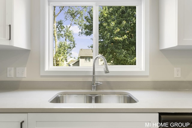 kitchen with dishwasher, white cabinetry, and sink