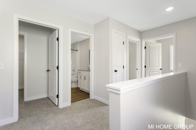 corridor featuring recessed lighting, baseboards, and light carpet