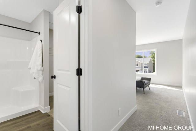 corridor featuring wood finished floors, baseboards, and visible vents