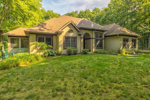 single story home with stucco siding, a shingled roof, and a front lawn