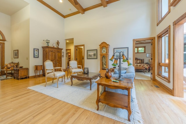 living room with crown molding, beamed ceiling, hardwood / wood-style flooring, and a high ceiling