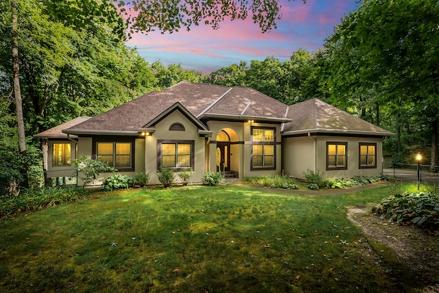 view of front facade with a lawn, fence, and stucco siding