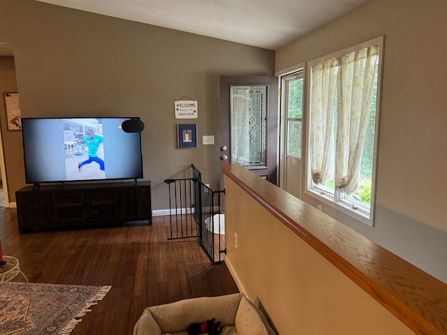 corridor featuring vaulted ceiling, a healthy amount of sunlight, and dark hardwood / wood-style floors