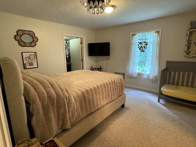 carpeted bedroom featuring a textured ceiling and a chandelier