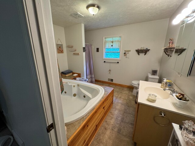 bathroom with vanity, toilet, a textured ceiling, and a bathtub