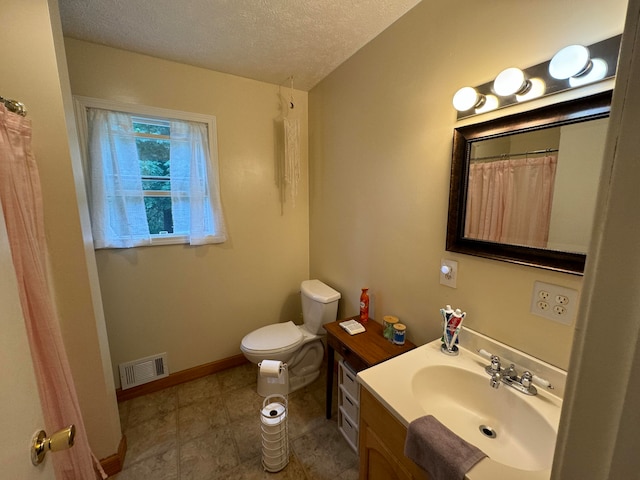 bathroom with vanity, toilet, and a textured ceiling