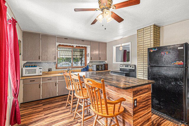 6991 E Apple Ave, Muskegon, MI 49442 - kitchen with white microwave, freestanding refrigerator, ceiling fan, stainless steel electric range oven, and wood finished floors