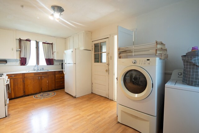 laundry area featuring light hardwood / wood-style flooring, washing machine and clothes dryer, and sink