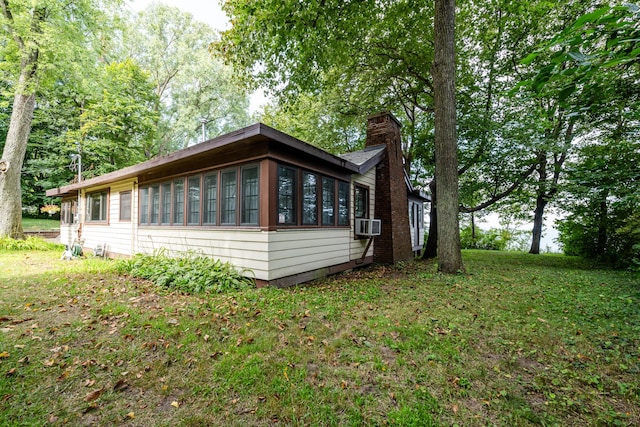 view of side of home featuring a yard, cooling unit, and a chimney