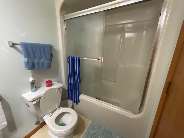 bathroom with enclosed tub / shower combo and toilet