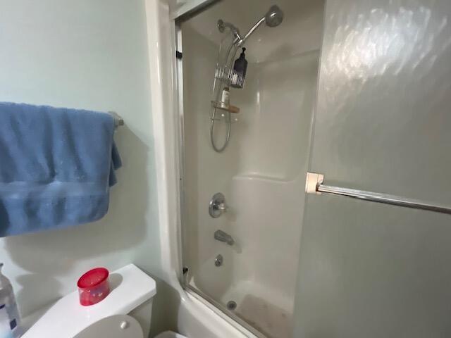 bathroom with enclosed tub / shower combo and toilet