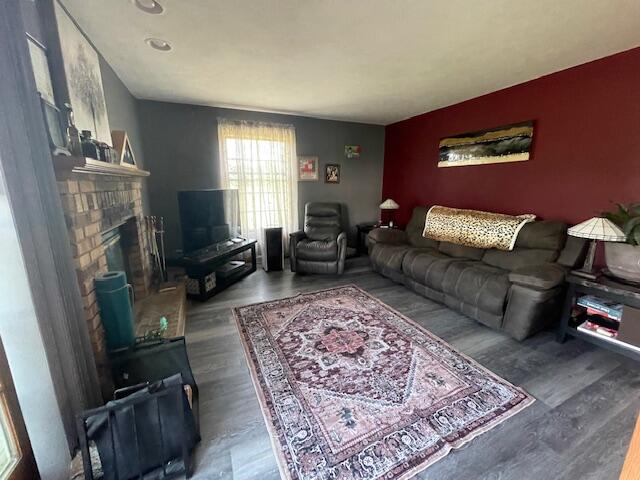 living room featuring wood-type flooring and a brick fireplace