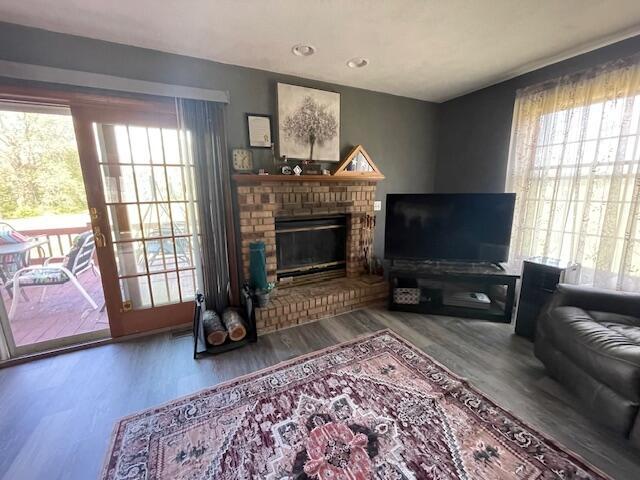 living room with a brick fireplace and wood-type flooring