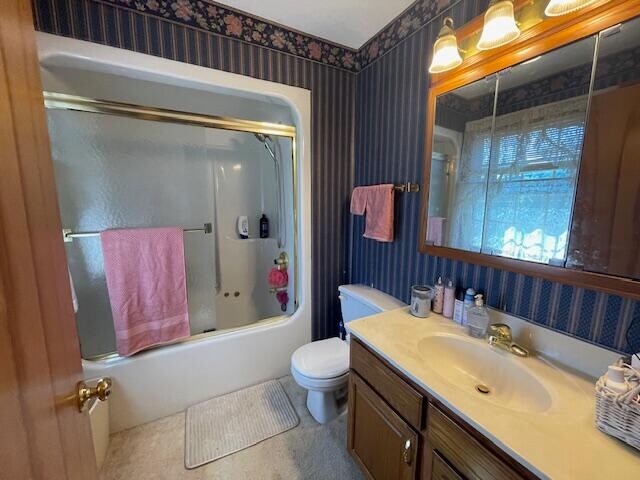 full bathroom featuring combined bath / shower with glass door, vanity, toilet, and tile patterned floors