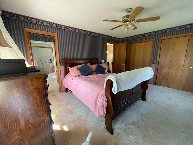 bedroom featuring ceiling fan, carpet, and multiple closets