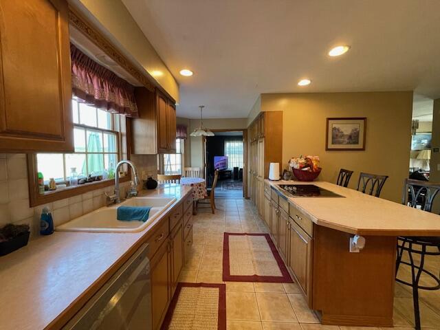 kitchen featuring backsplash, a kitchen bar, hanging light fixtures, sink, and light tile patterned flooring