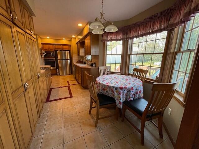 dining space with light tile patterned floors, a notable chandelier, and sink