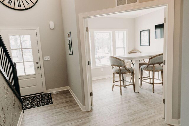 foyer featuring ornamental molding and light hardwood / wood-style flooring