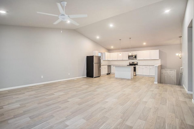 kitchen with white cabinets, lofted ceiling, decorative light fixtures, appliances with stainless steel finishes, and ceiling fan with notable chandelier