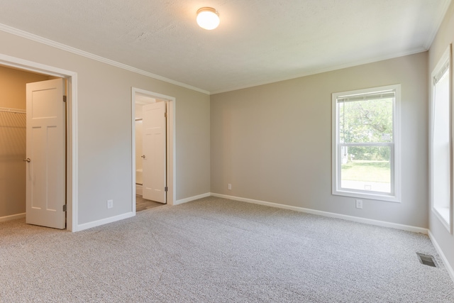 unfurnished bedroom with light carpet, crown molding, a closet, a spacious closet, and ensuite bathroom