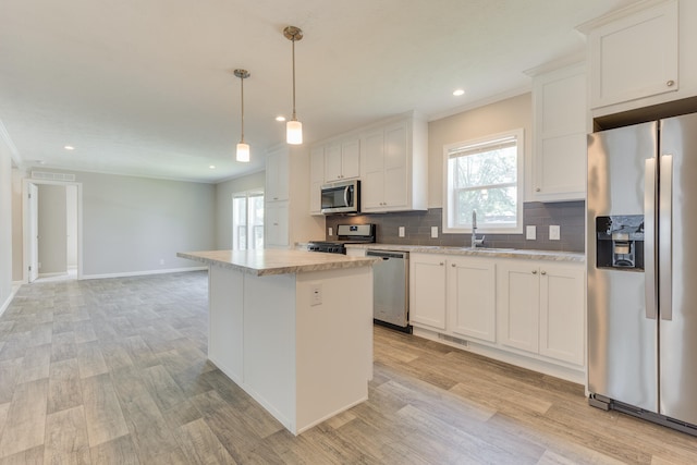 kitchen featuring white cabinetry, a healthy amount of sunlight, a kitchen island, and stainless steel appliances