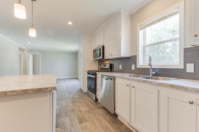 kitchen featuring light wood-type flooring, appliances with stainless steel finishes, white cabinetry, sink, and decorative backsplash