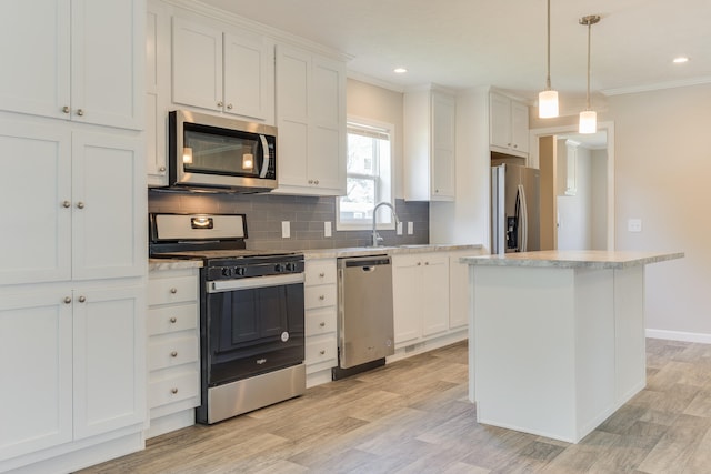 kitchen with light wood-type flooring, appliances with stainless steel finishes, white cabinetry, and a kitchen island