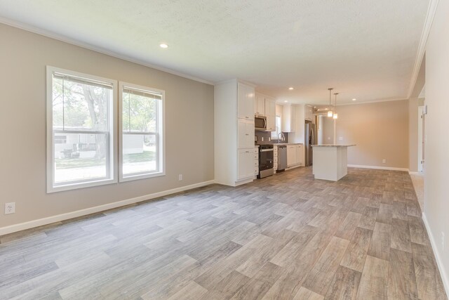 unfurnished living room with light wood-type flooring, crown molding, and a healthy amount of sunlight