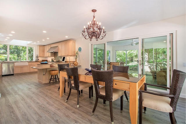 dining room with ceiling fan with notable chandelier, light hardwood / wood-style floors, and sink